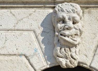 Mascheron a sculpture of a deformed face over a wall in Venice